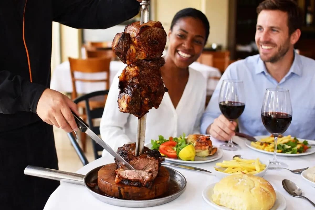 Asado y vino en restaurante en Buenos Aires, Argentina Primer plano de turistas disfrutando de un asado tradicional argentino y los mejores vinos de la zona, en un restaurante de la ciudad de Buenos Aires