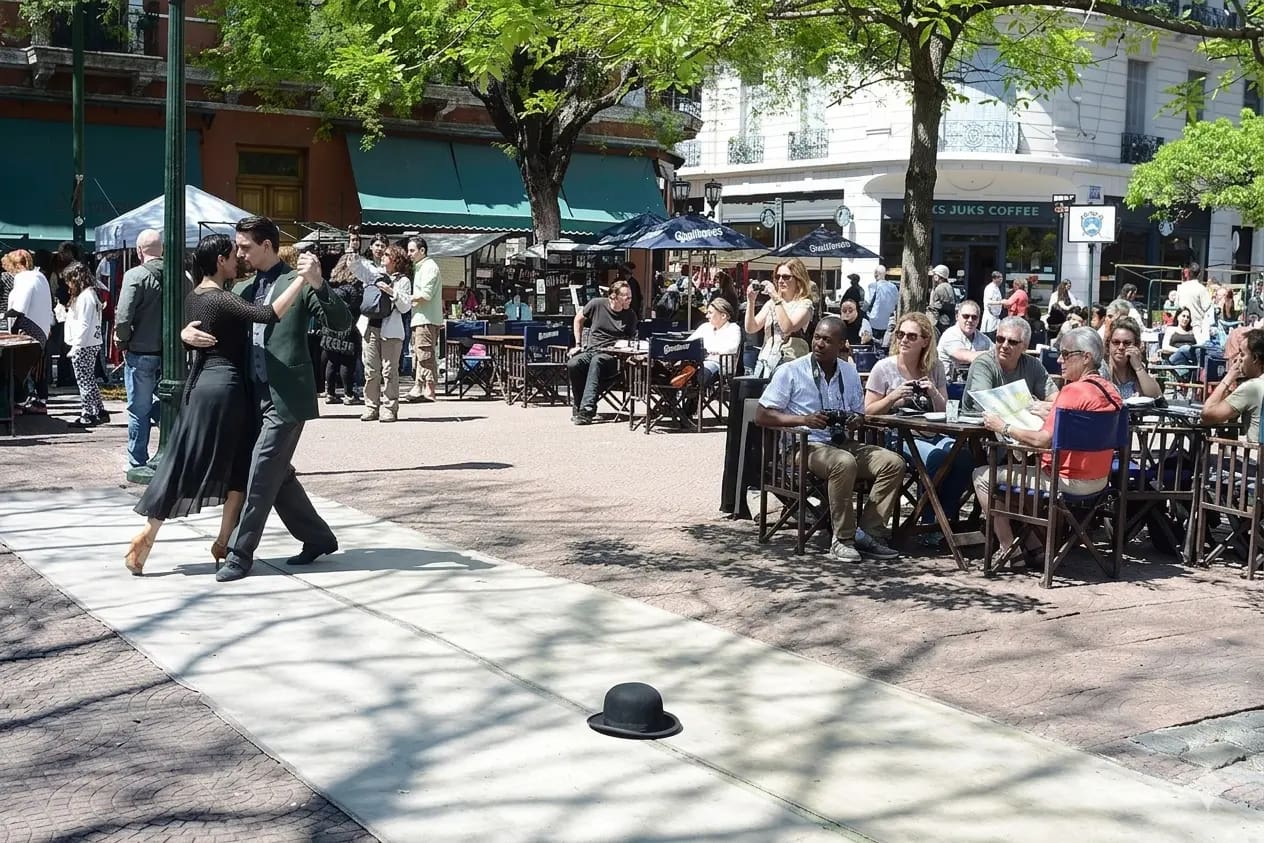 Pareja bailando tango en callle peatonal, frente a un café de la ciudad. El tango se baila con frecuencia en las calles de Buenos Aires. Si eres extranjero, no temas que te inviten a bailar. Los locales suelen asumir que no sabes bailar tango correctamente.